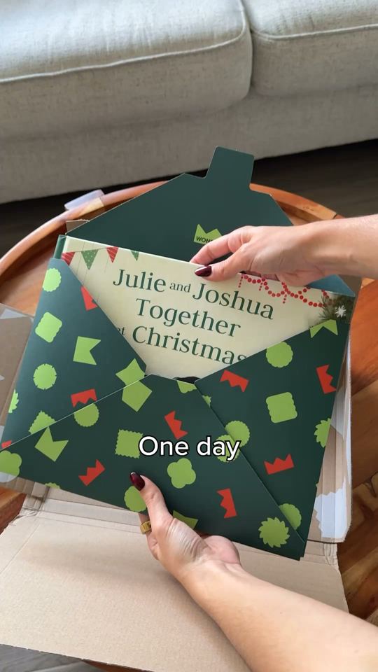 Hands opening a green envelope with a Christmas book inside, caption: One day